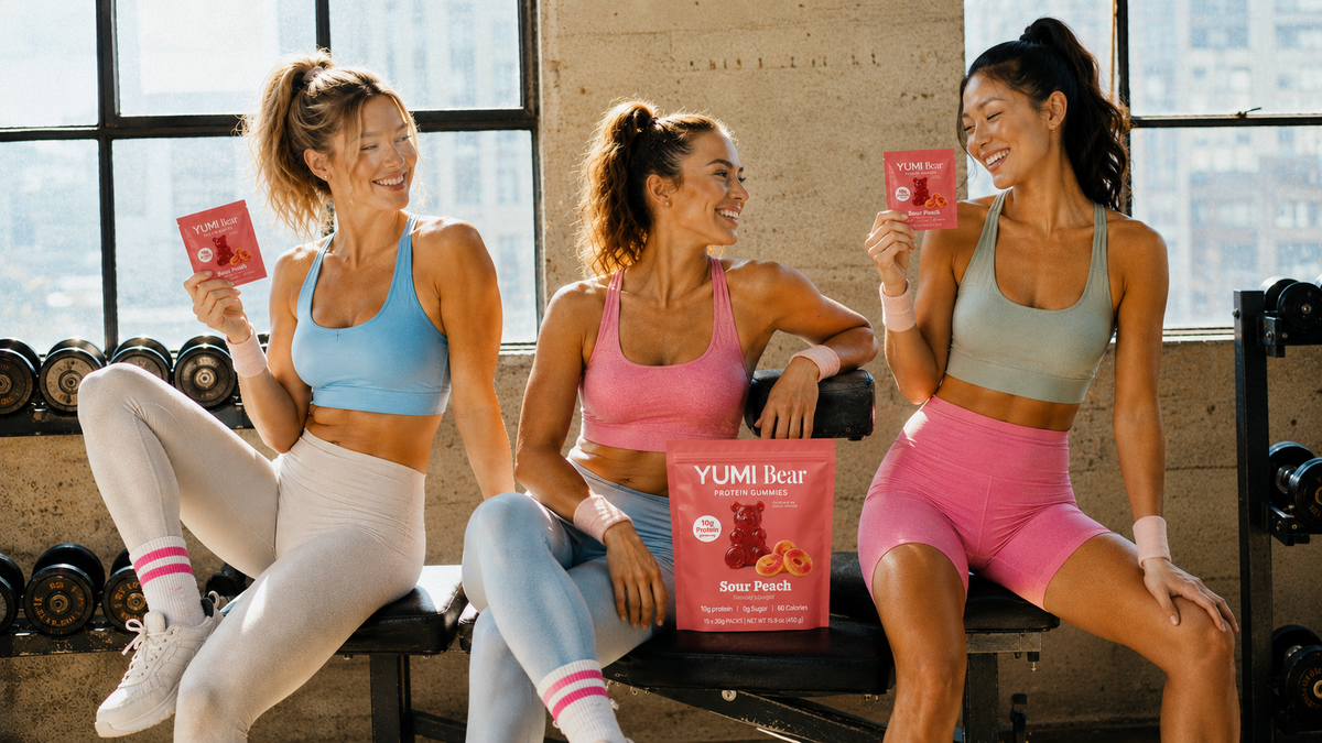 Friends enjoying YUMI Bear protein gummies at the gym