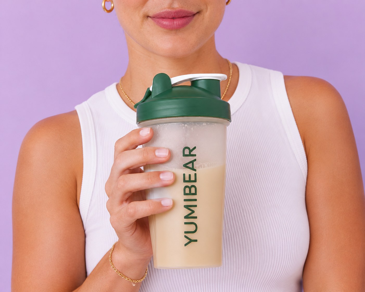 Woman holding a YUMI Bear protein shaker against a pastel purple backdrop
